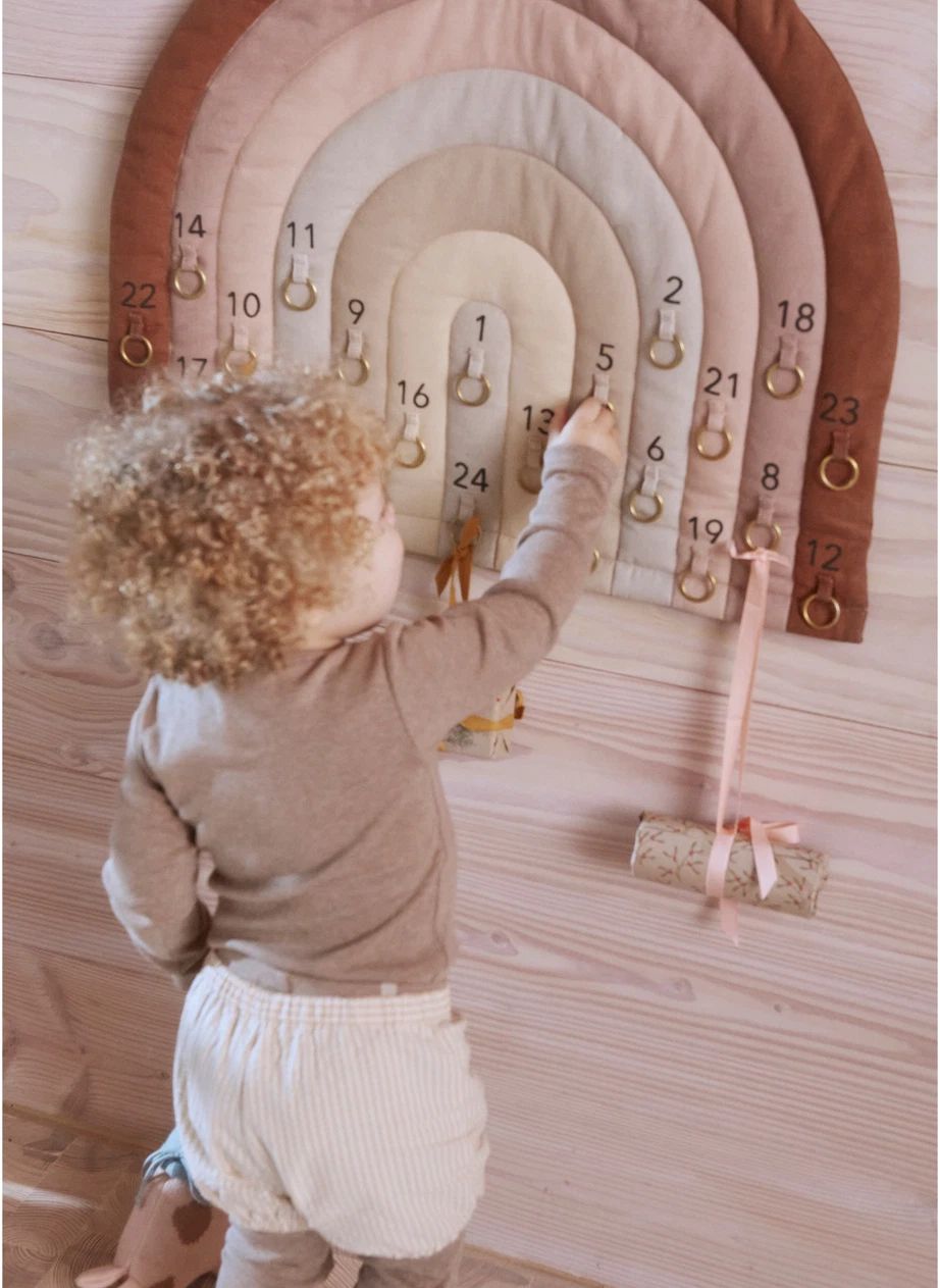 Enfant décrochant un paquet du calendrier de l'Avent Arc-en-ciel OYOY Mini