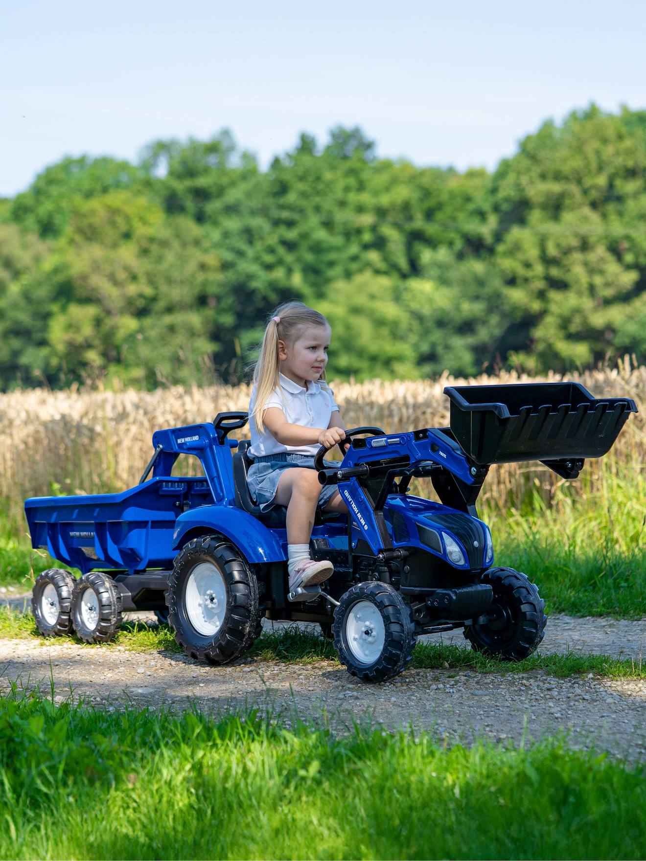 Tractopelle à pédales avec excavatrice arrière, selle pivotante et remorque double essieux basculante bleu new holland